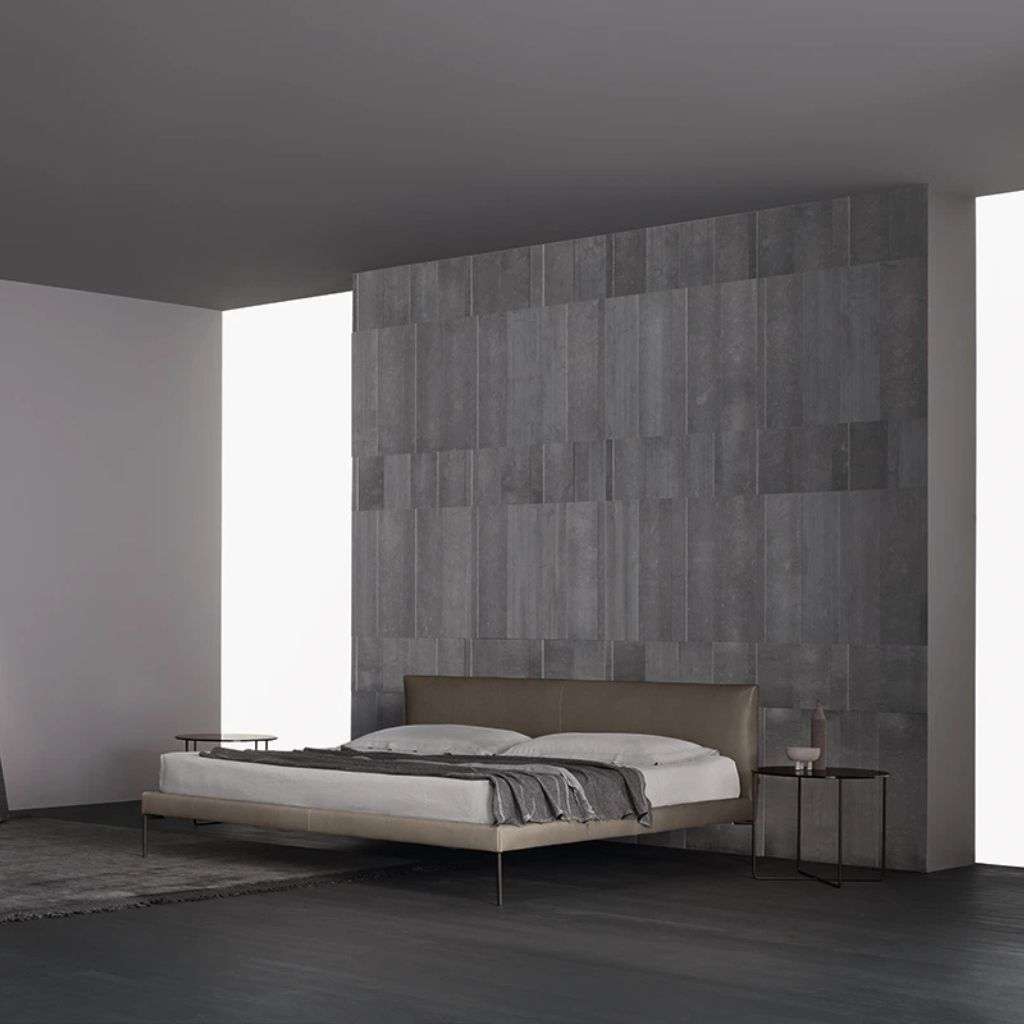 Amura minimalist bedroom design with a grey stone wall and modern bed. 