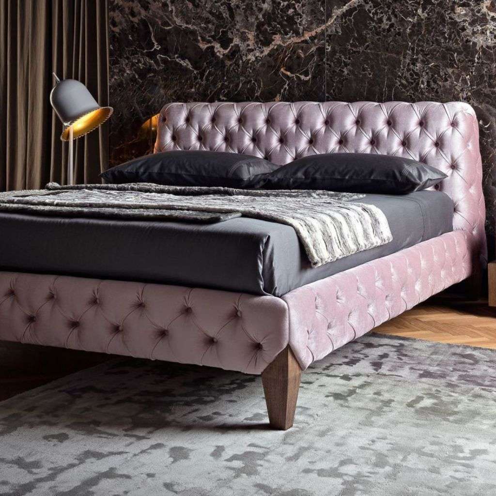 Bamax bedroom with a pink velvet tufted bed and dark marble accent wall.