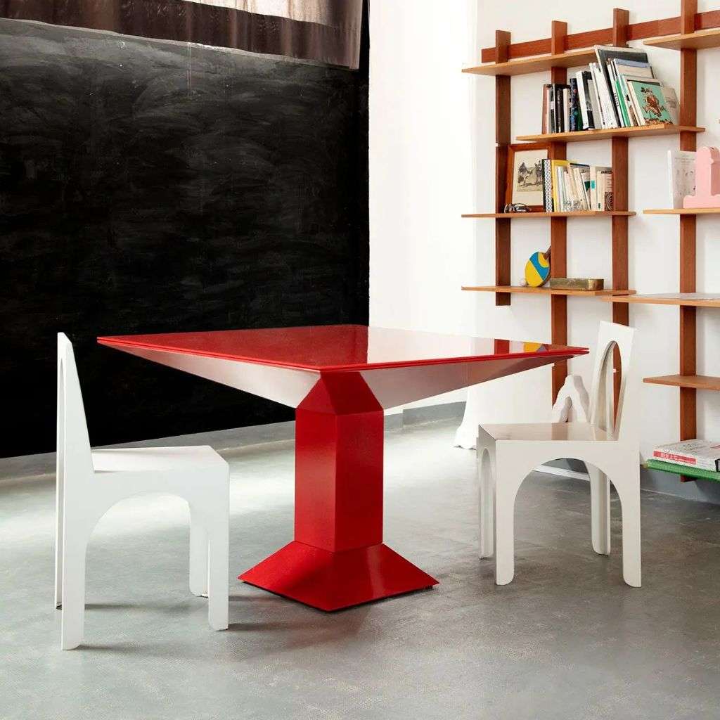 Red BD Barcelona table with white chairs and a wooden shelf.