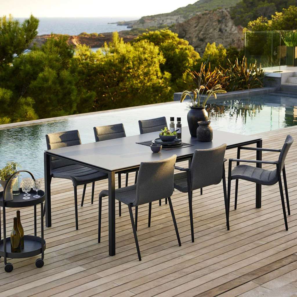 Cane-line Core dining set in charcoal by the pool with sea view.