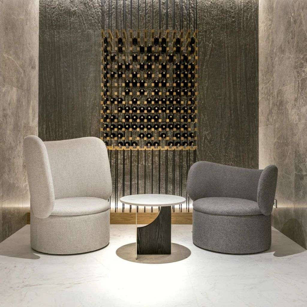 Cozy lounge with a plush curved armchair and minimalist rug from Collection Alexandra.