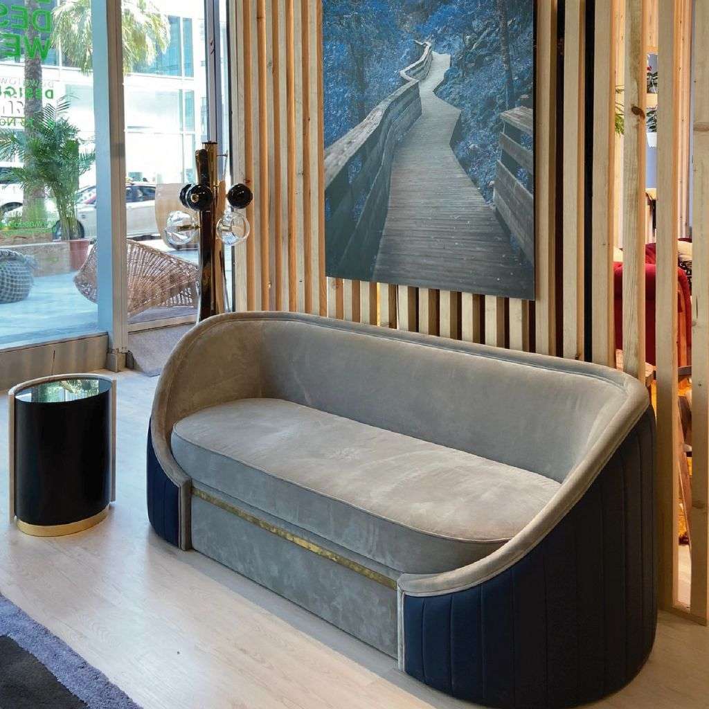 Duquesa & Malvada curved grey velvet sofa with navy base and brass trim