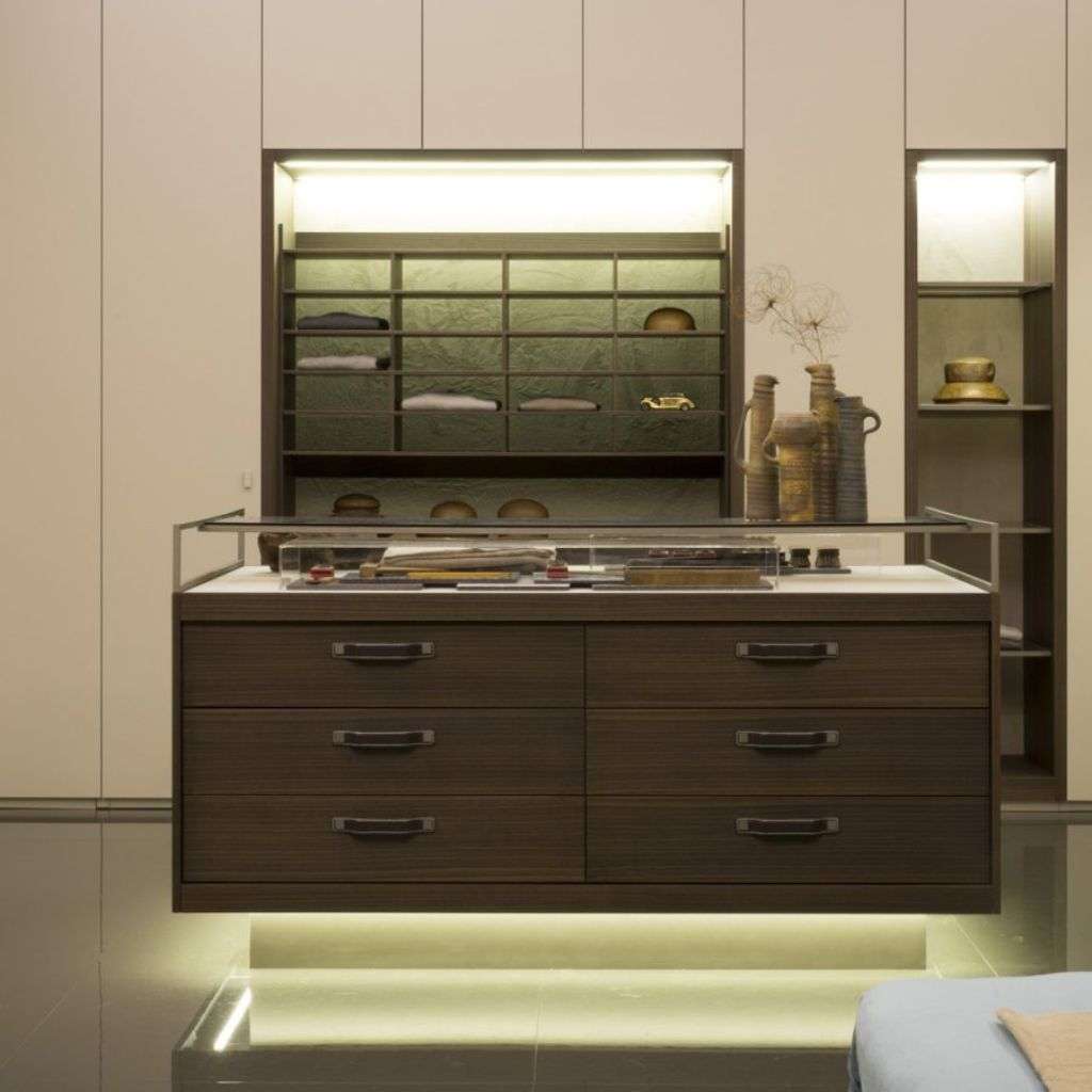 Emmebi wardrobe island with glass top display, dark wood drawers and soft LED base.