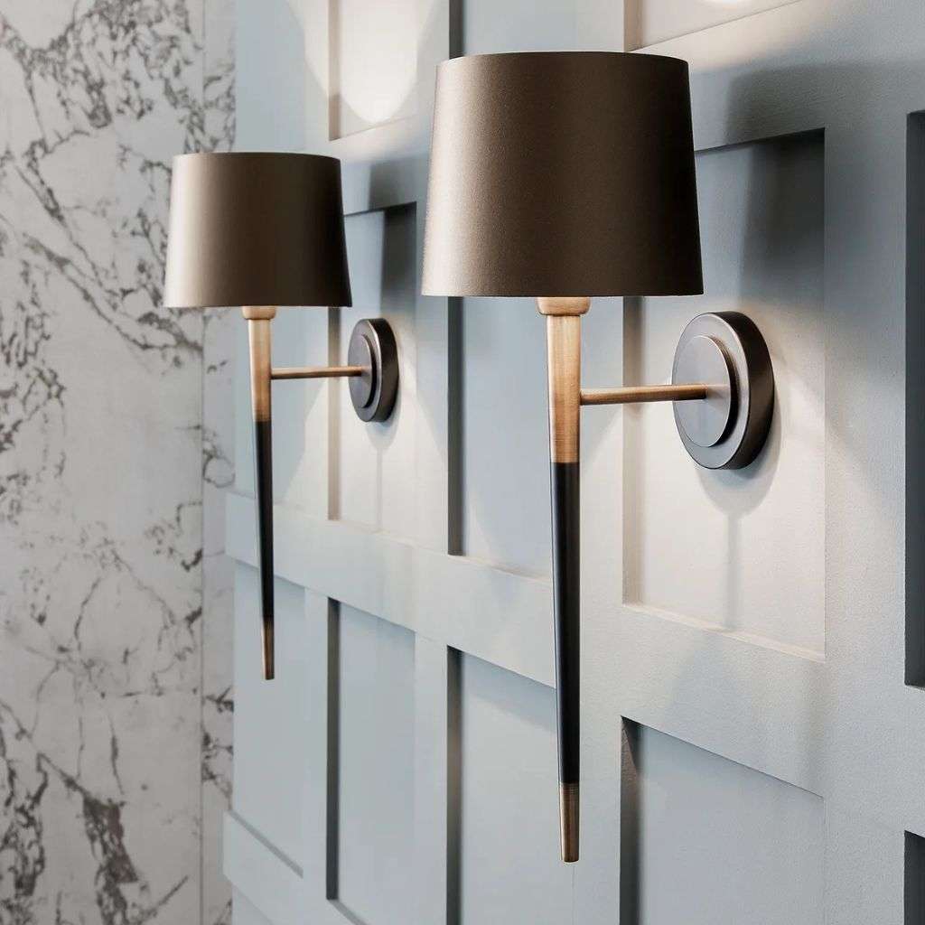 Heathfield brass and black tapered wall lights on panelled wall with marble detail