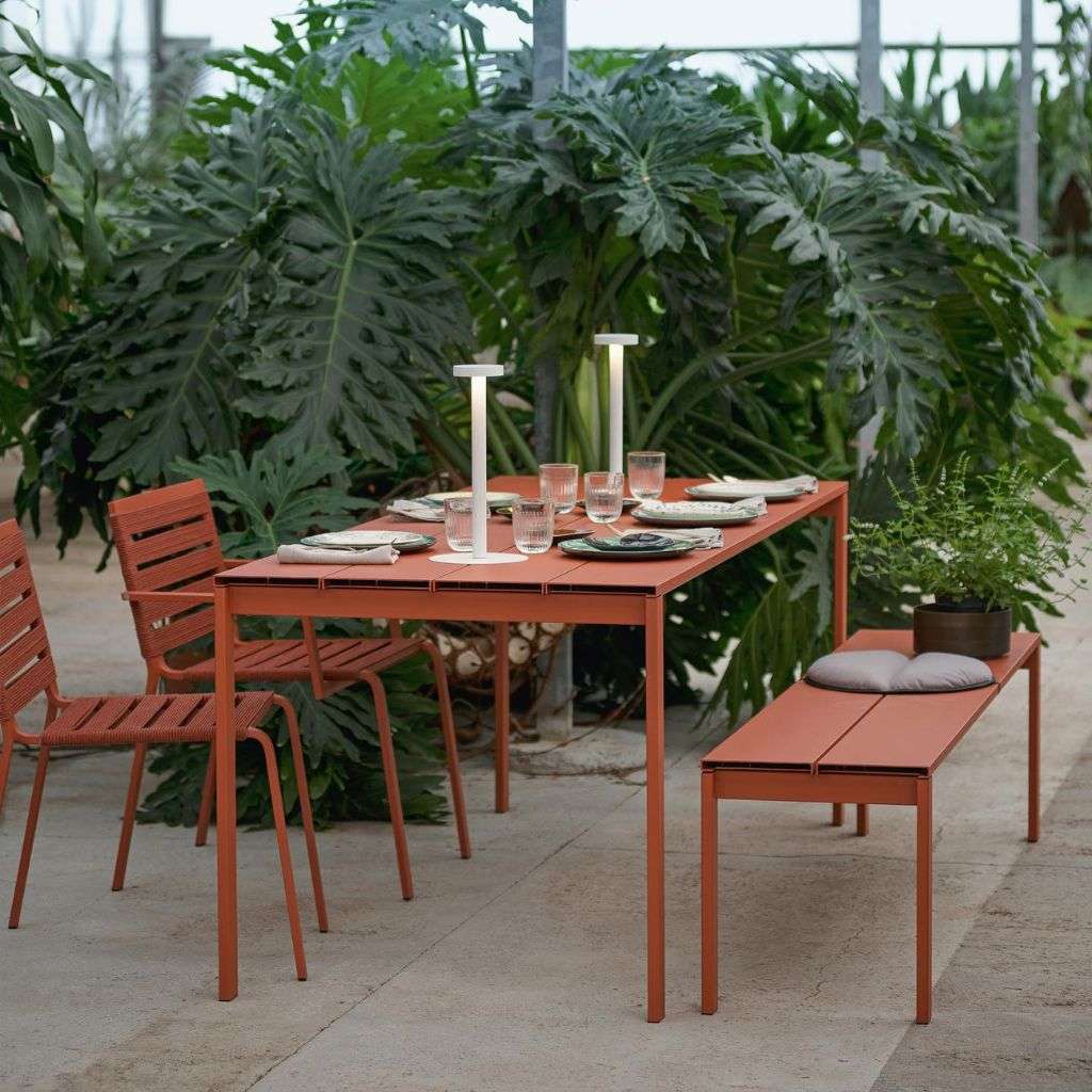 Kristalia outdoor dining table and chairs amidst lush greenery in a garden setting.