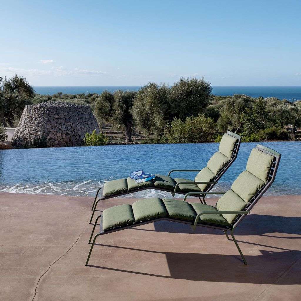 Kristalia outdoor poolside loungers with a scenic backdrop of greenery and the ocean.