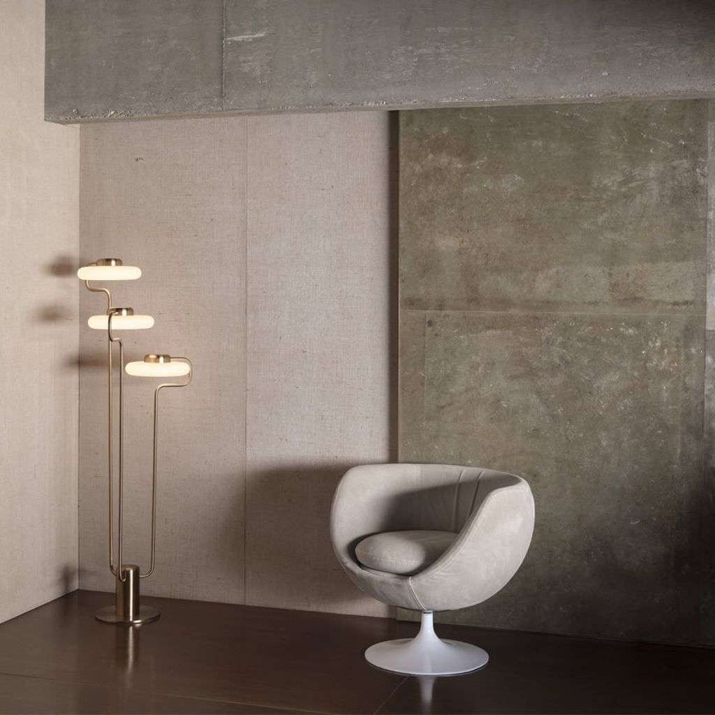 KDLN three-disc brass floor lamp beside a sculptural chair.