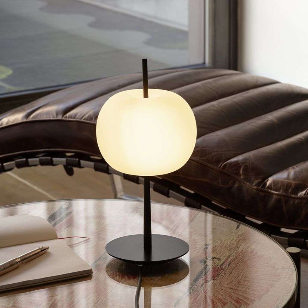 KDLN opal globe table lamp on black base beside a leather chaise.