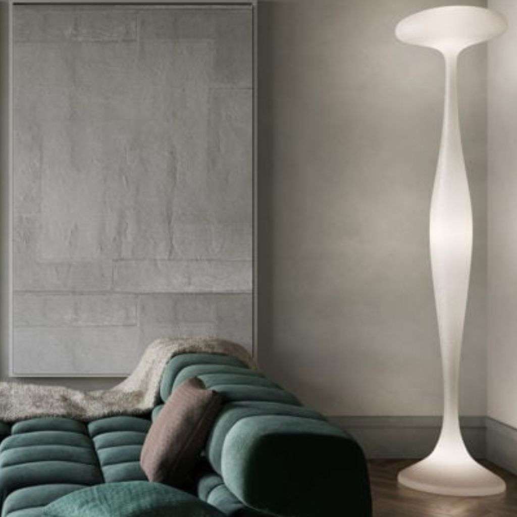 organic white floor lamp beside a deep green modular sofa.