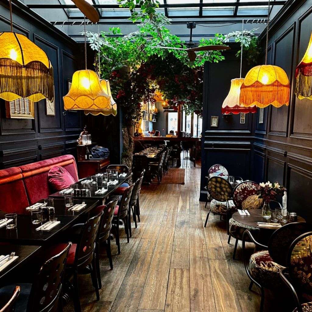 La Fibule dining area featuring vintage-inspired lighting and rustic furniture.