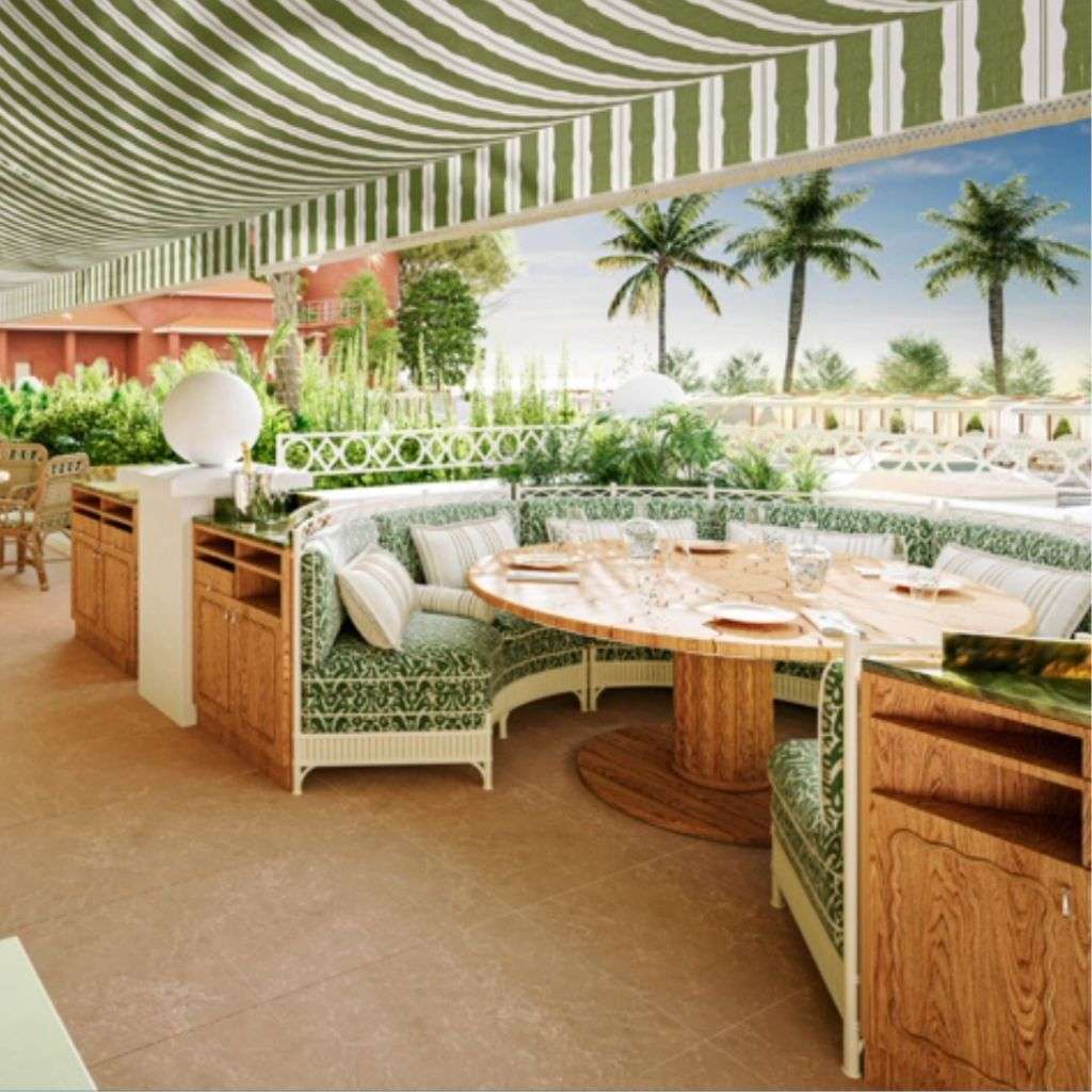La Fibule outdoor dining space with a striped canopy and green upholstery.