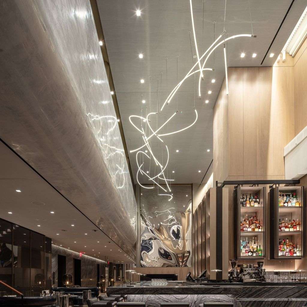 Lasvit sinuous linear light installation animating a modern bar.