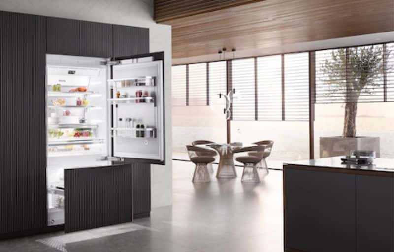 Miele built-in fridge-freezer open, integrated into dark ribbed cabinetry.
