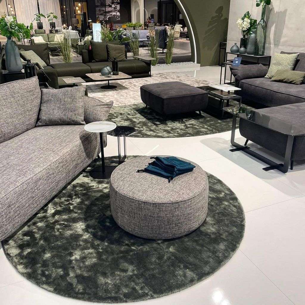 miinu circular moss-tone rugs styling a contemporary seating display with ottoman tables.