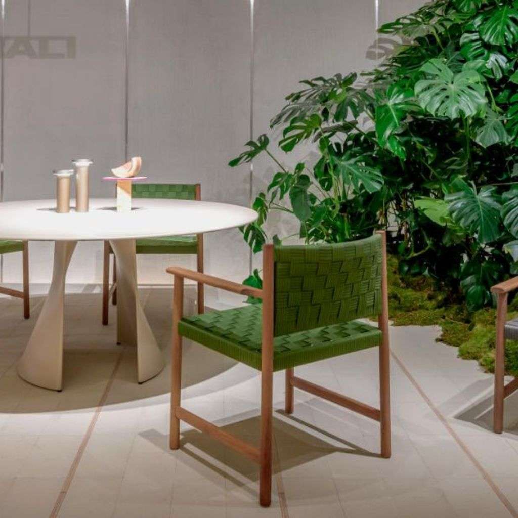 Pedrali elegant dining table with modern woven chairs surrounded by lush greenery.