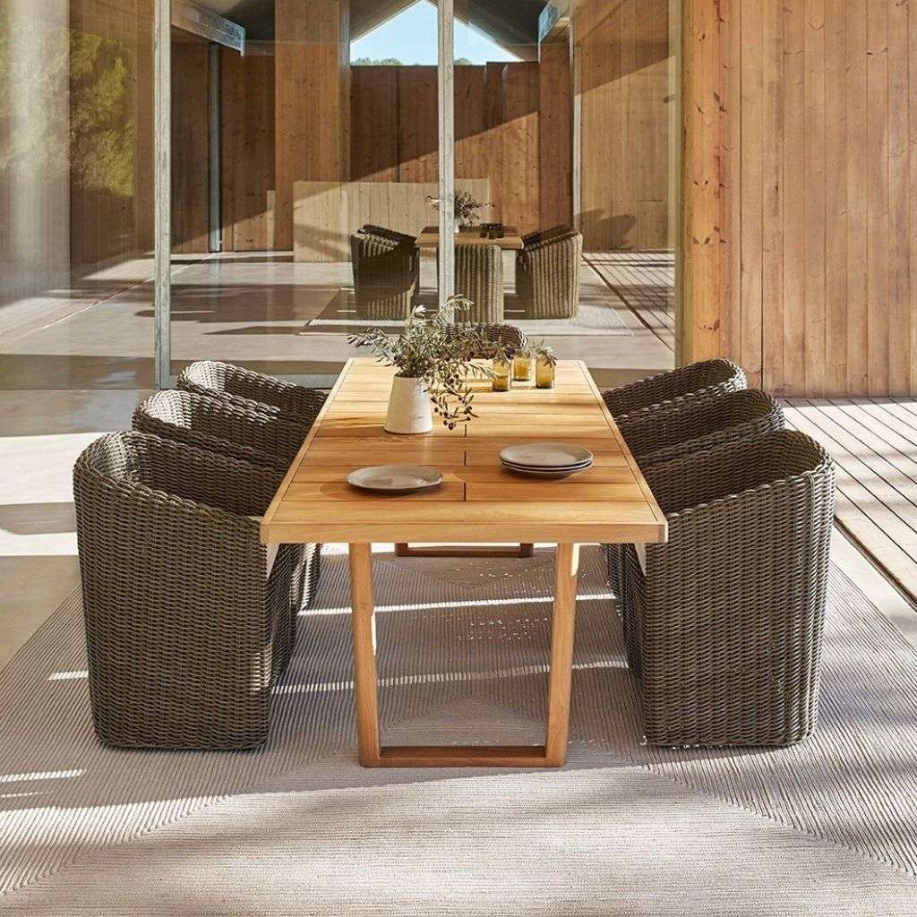 Point outdoor dining table and chairs with wicker bases and wooden tops.