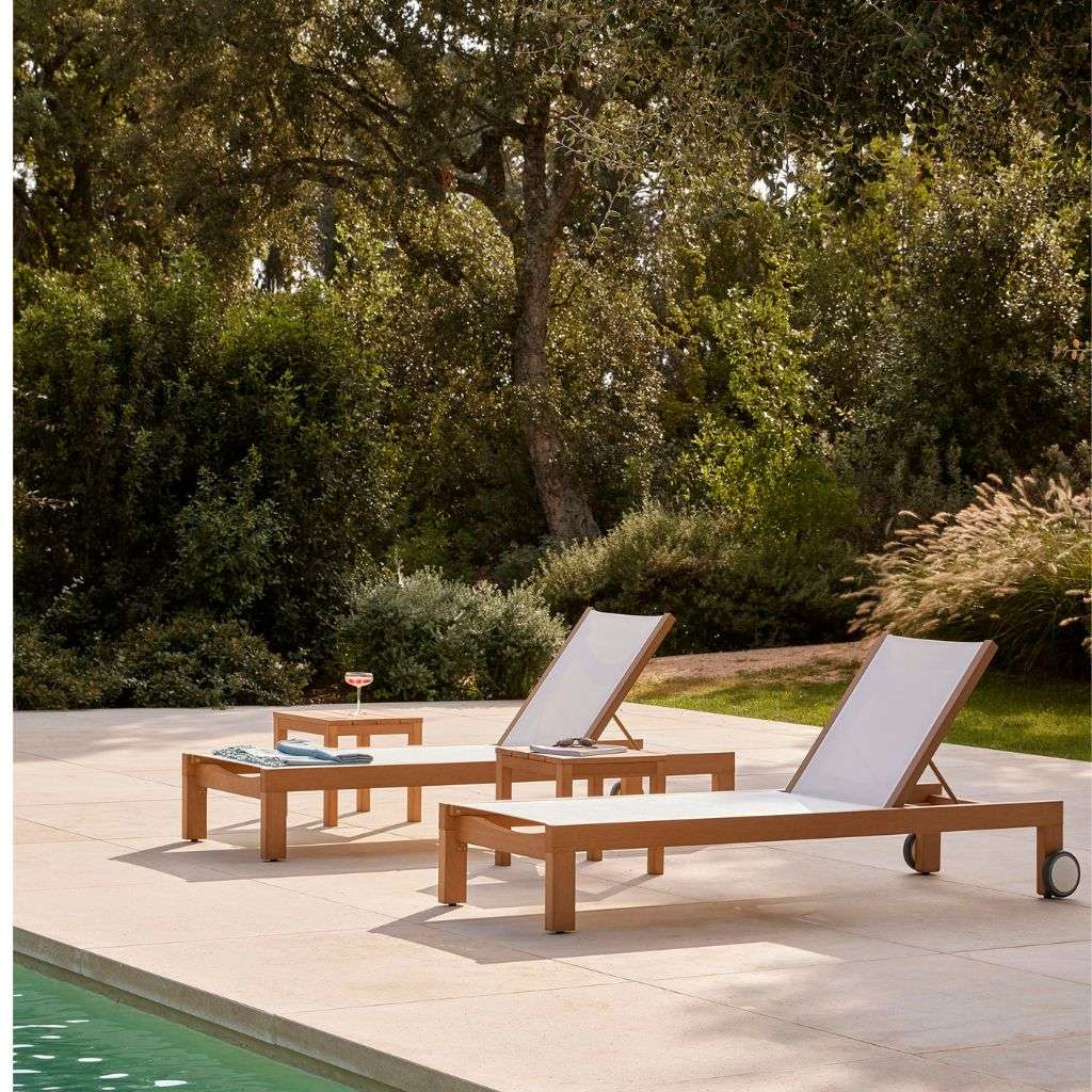 Point poolside loungers with wooden frames and clean white cushions for relaxation.