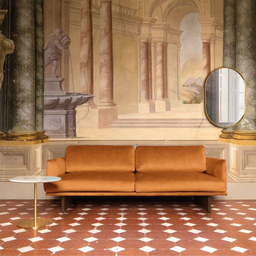Quinti sofa in front of a classical mural, blending luxury with timeless design.