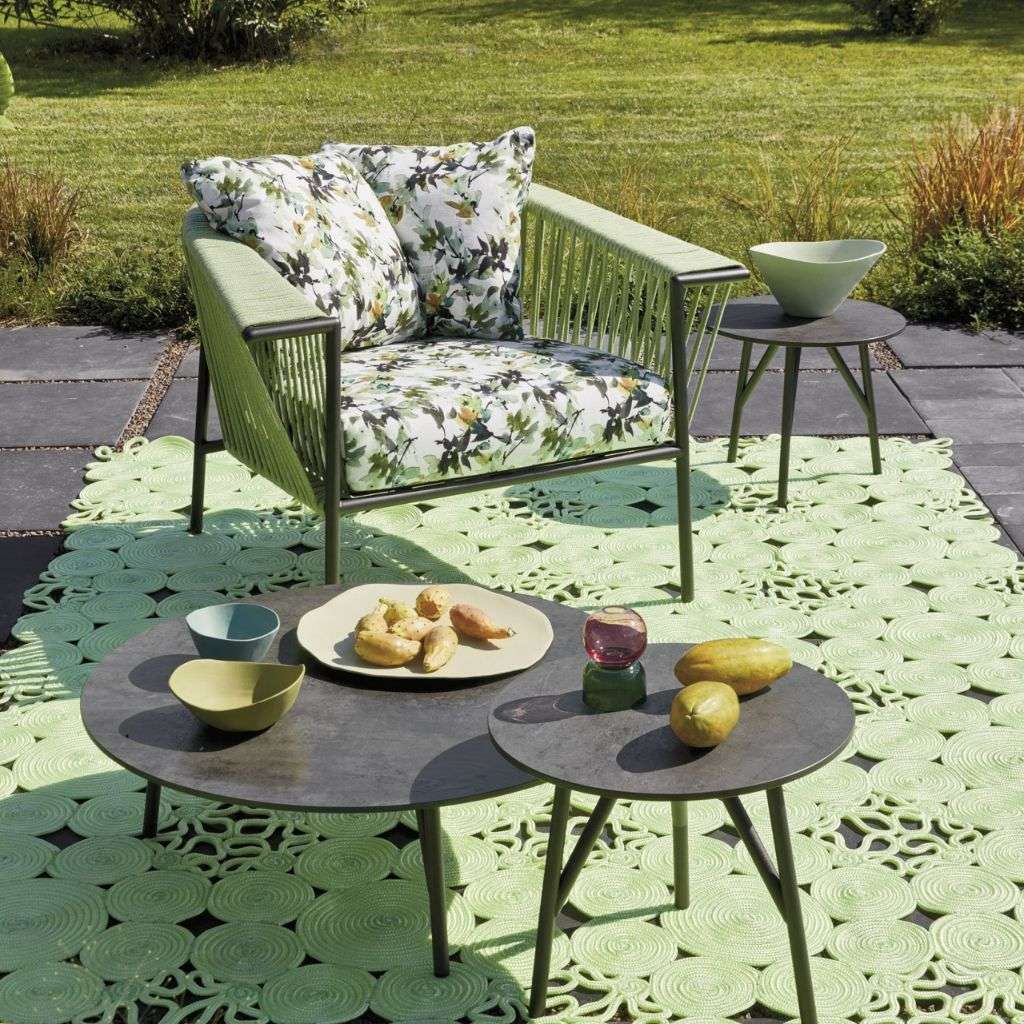 Roberti Rattan chair with floral cushion, green accents, and modern outdoor table.