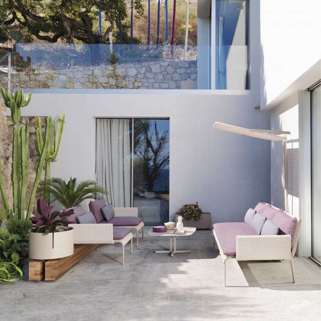 Roberti Rattan seating with vibrant accents and modern rug in a spacious living room.