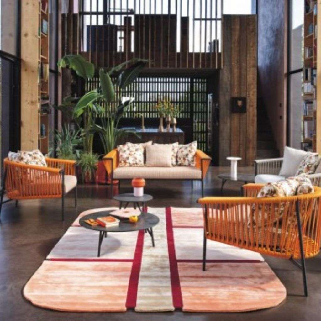 Roberti Rattan seating with vibrant accents and modern rug in a spacious living room.