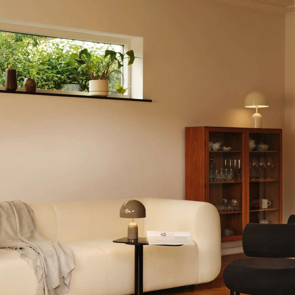 Modern living room with a cozy sofa, plants, and ambient lighting by Tom Dixon.