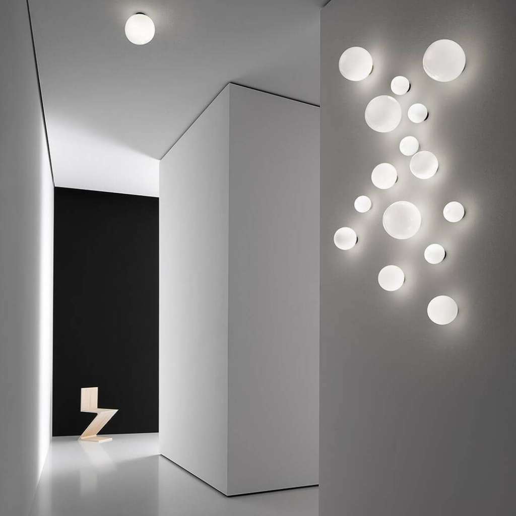 Vesoi wall cluster of glowing round lights in a white hallway.