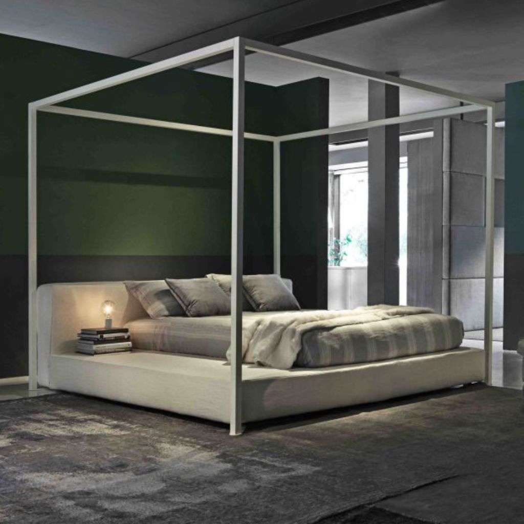 Villevenete minimalist four-poster bed with white upholstery and soft grey linens in a luxurious room.