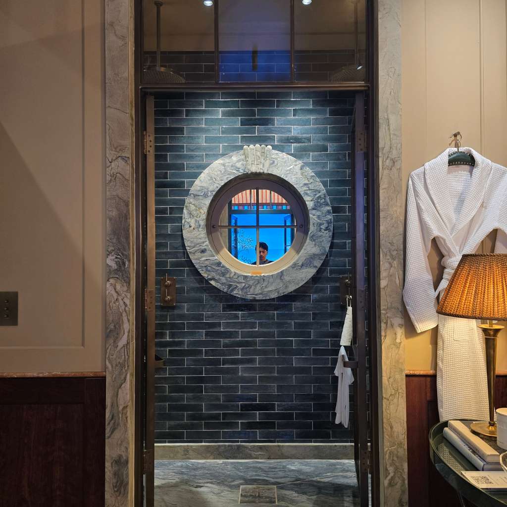 Luxury bathroom featuring layered materials, intricate detailing, marble surrounds and statement circular window