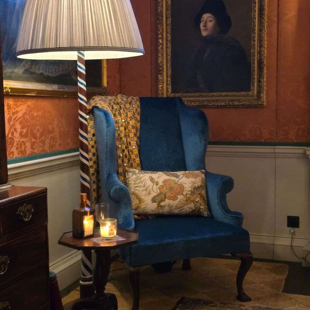 Maximalist living room with blue velvet armchair, floor lamp and vintage artwork