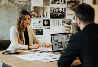 Interior designers collaborating at a desk with mood boards and laptop.