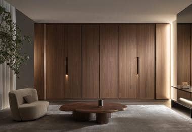 Walnut fitted wardrobe with integrated handles in a minimalist dressing room.