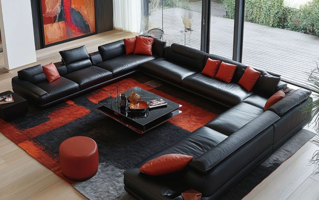 Black leather sectional sofa with orange pillows and a modern rug.