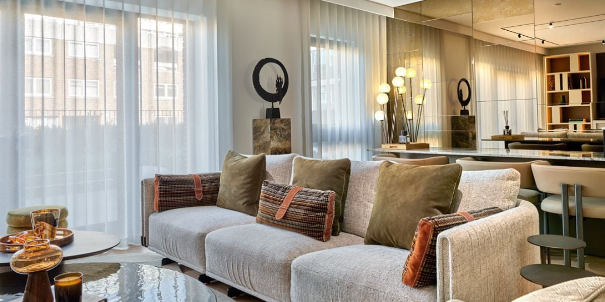 Compact open plan living room with full antique mirror wall, neutral textured sofa, sheer curtains and dining bar area reflected beyond