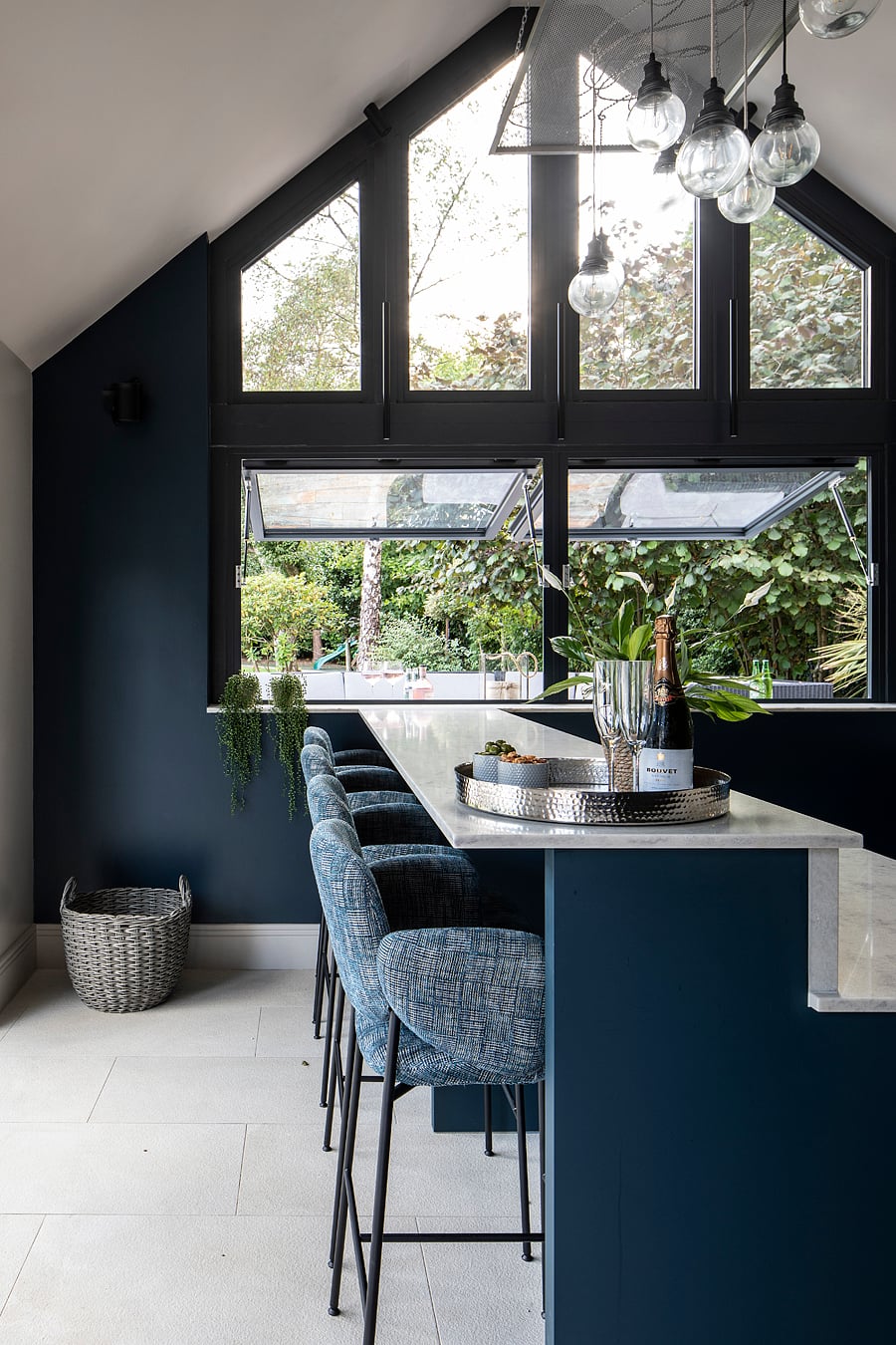 Marble bar counter with upholstered stools against navy blue kitchen cabinetry