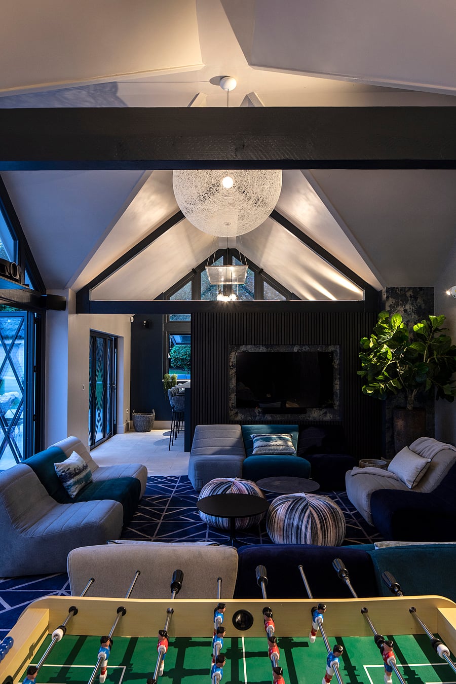 Blue and navy pool house lounge with vaulted ceiling and entertainment area