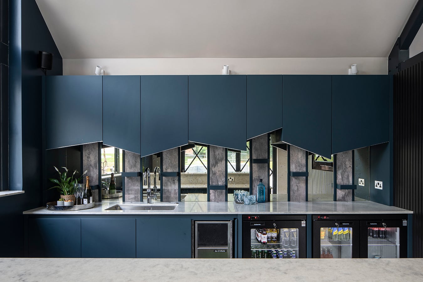 Exposed filament bulb pendant lights hanging over navy blue kitchen bar counter