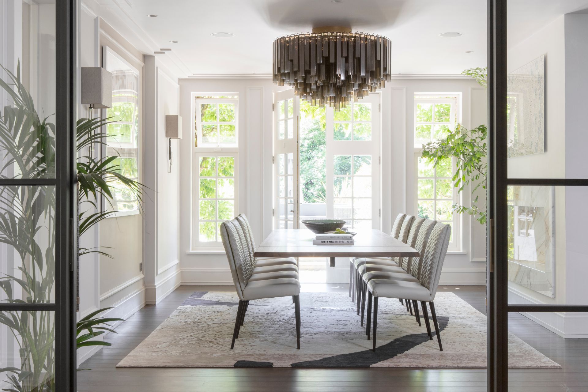 Dining area with a chandelier and a sleek bar with wine coolers.