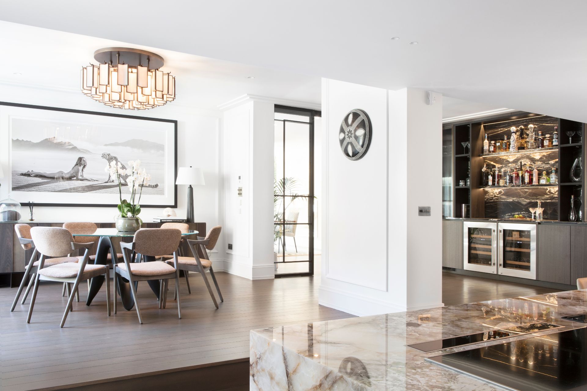 Elegant kitchen with a marble countertop, wine fridge, barstools, and stylish cabinetry.