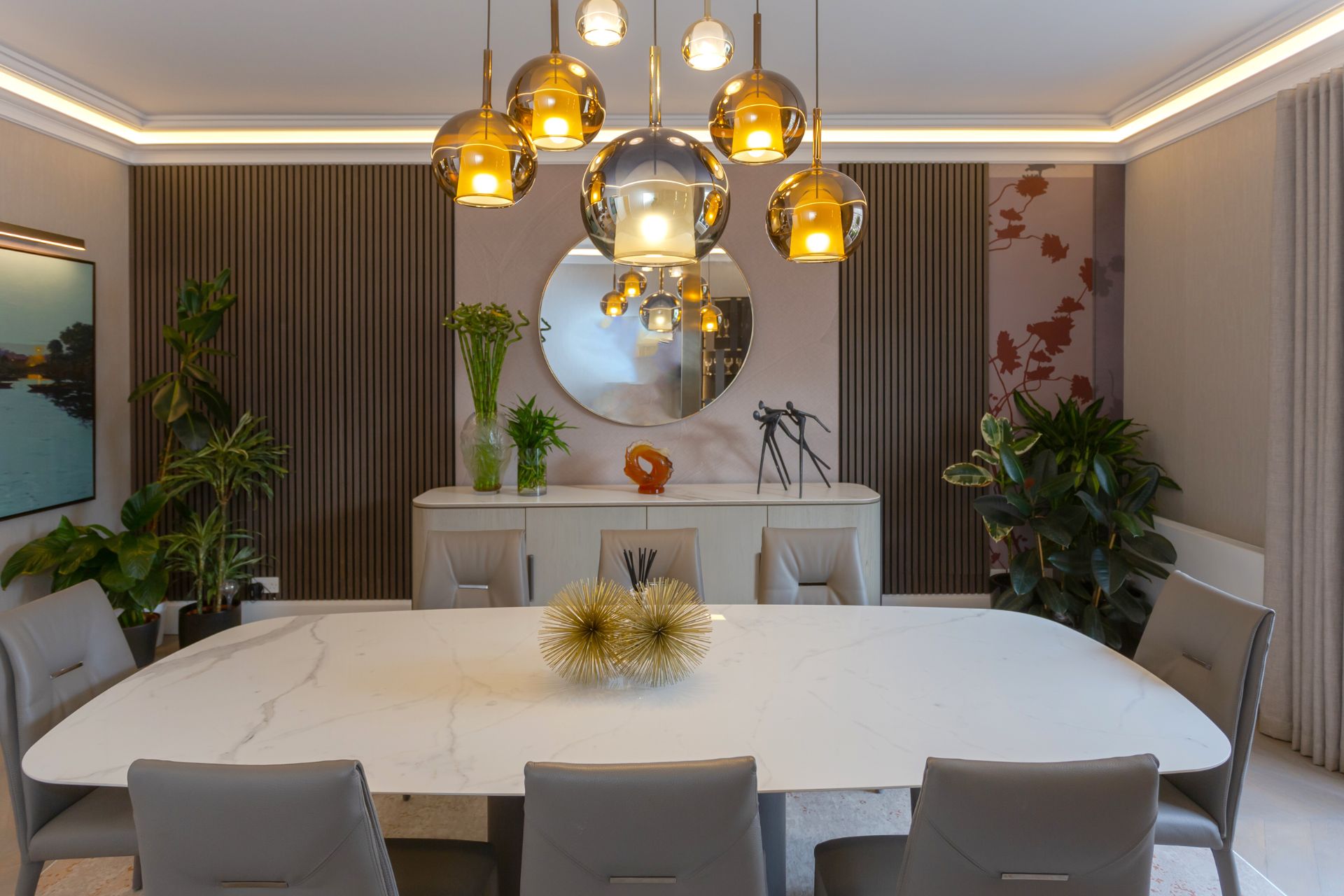 Elegant dining room with a marble table, stylish pendant lights, and decorative plants.