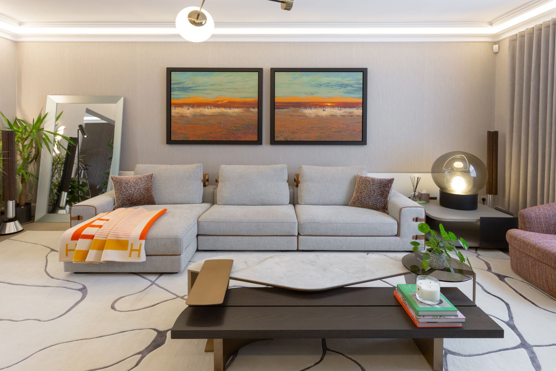 Modern living room with a large sofa, abstract artwork, and statement lighting.