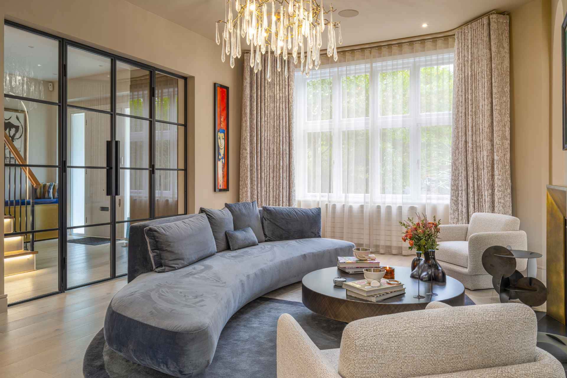 Living room with curved velvet sofa, coffee table, and modern chandelier