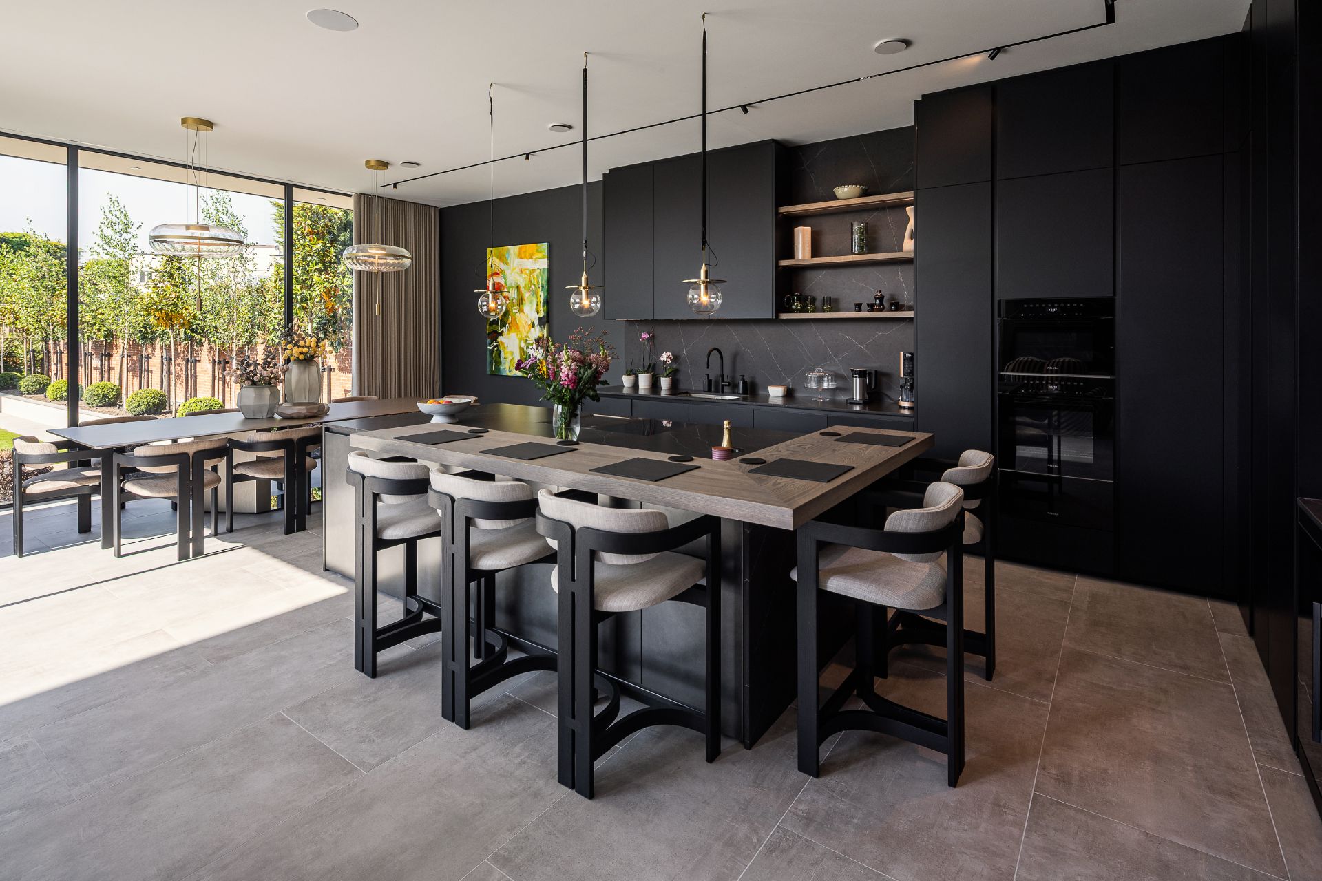 Elegant kitchen with black cabinetry, pendant lighting, and a large island.